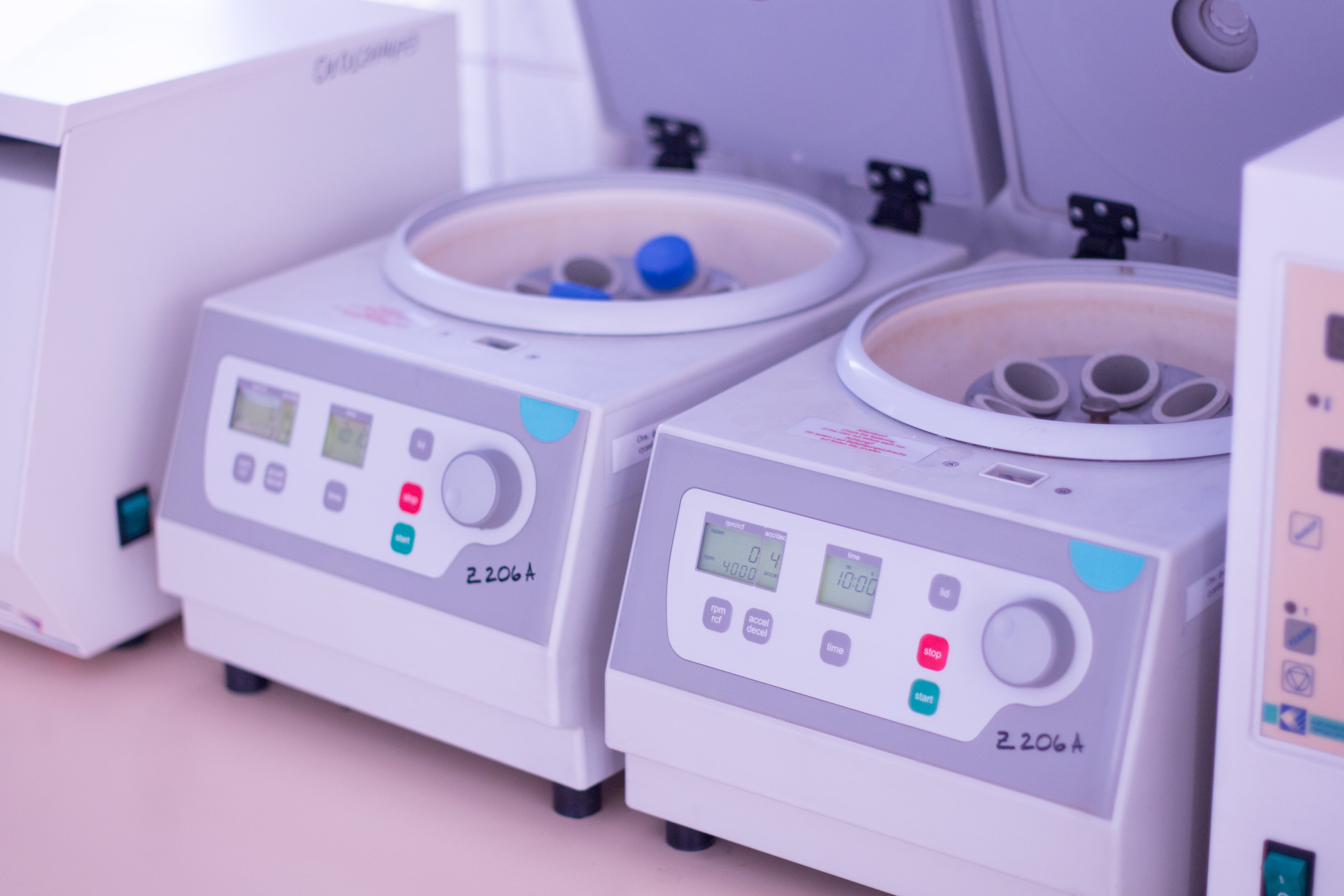 Two benchtop laboratory centrifuges with blood sample tubes loaded in the rotors