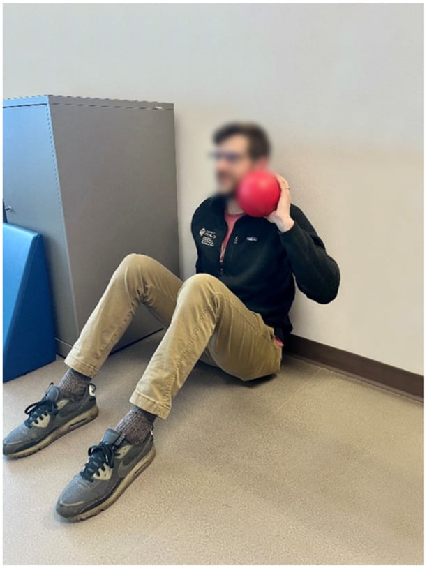 Seated single-arm shot-put test for upper-extremity power, the athlete sitting on the floor against a wall with a ball at the shoulder