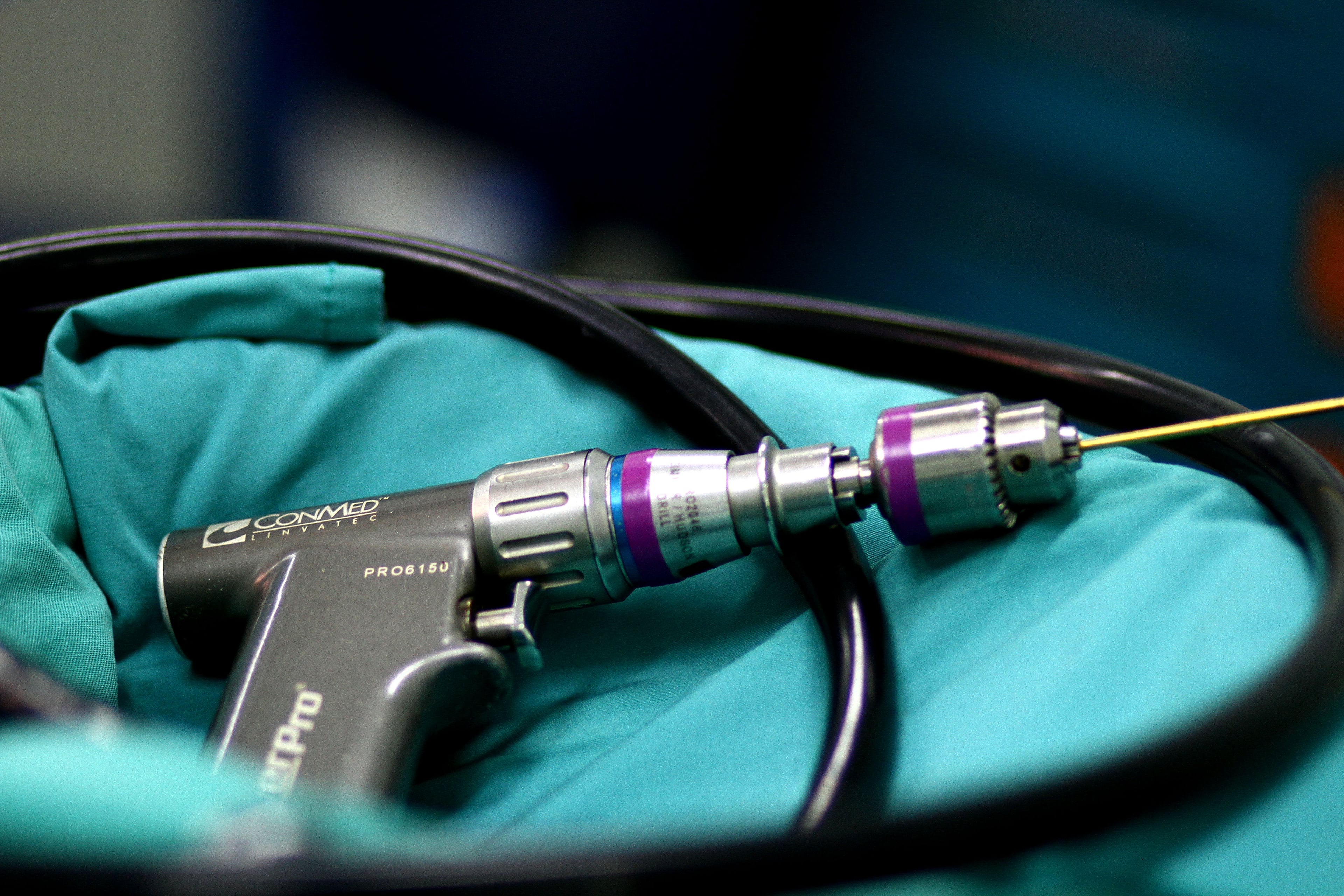 Pneumatic orthopaedic drill with handpiece, air hose, chuck and mounted wire.