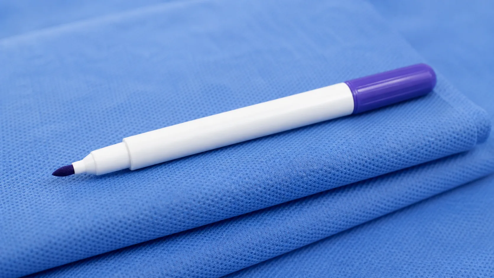 A sterile surgical skin marker pen resting on a folded blue drape