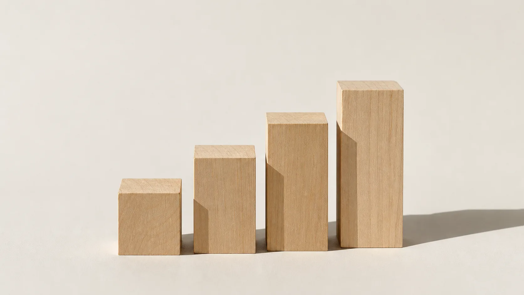 Four wooden blocks arranged as an ascending staircase on a pale surface