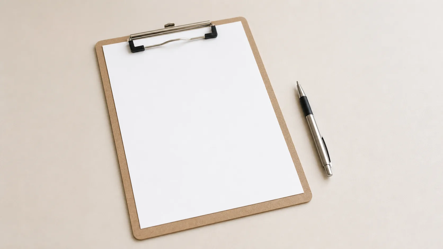A plain clipboard holding a blank sheet of paper resting on a clinic desk beside a pen