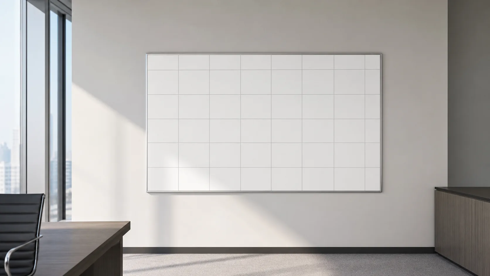 A wall-mounted calendar-sized blank grid board in an empty office with soft daylight across it