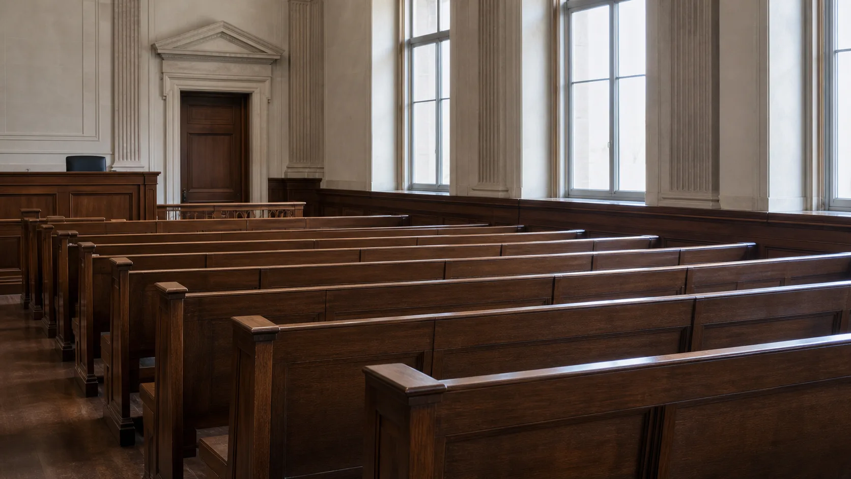 Rows of empty wooden public gallery benches in a formal courtroom