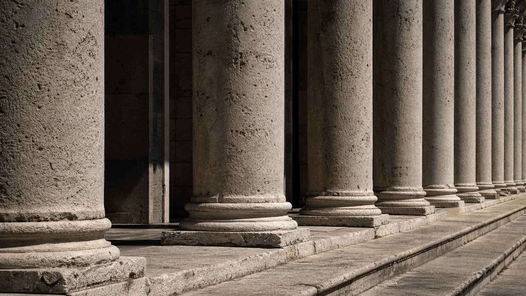 A classical stone portico with a row of weathered columns receding